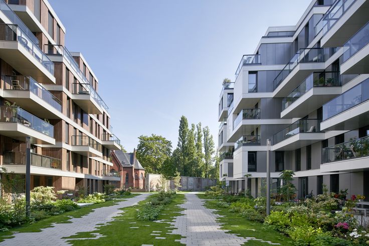 an empty walkway between two buildings with grass growing on each side and flowers in the middle