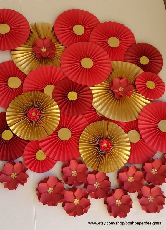 red and gold paper flowers are arranged on the wall