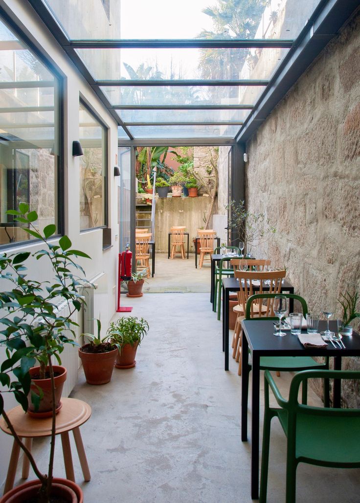 an indoor dining area with tables and chairs, potted plants on either side of the table