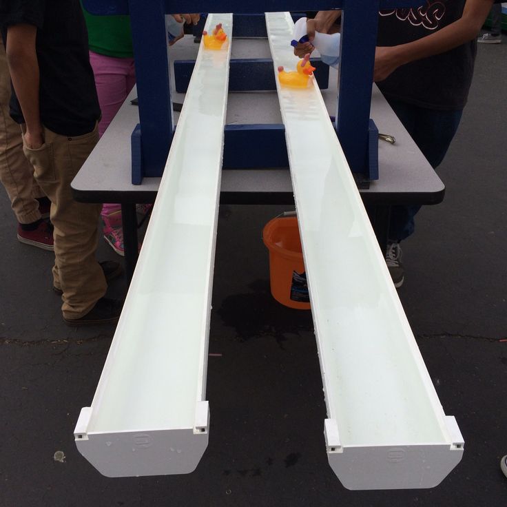 two people are standing next to each other in front of a conveyor belt with orange juices on it