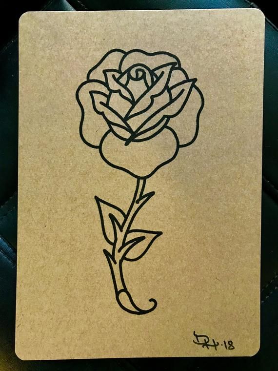 a drawing of a single rose on a piece of paper that is sitting on a table