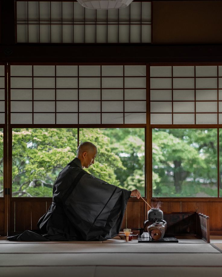 a man sitting on top of a bed next to a table with a tea pot