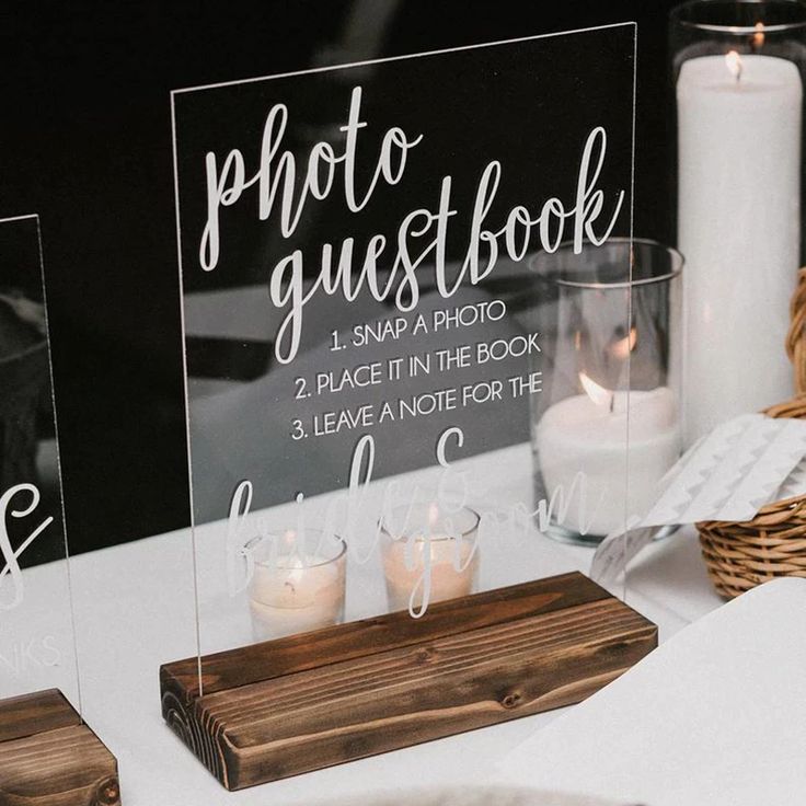 two clear acrylic signs sitting on top of a table next to some candles