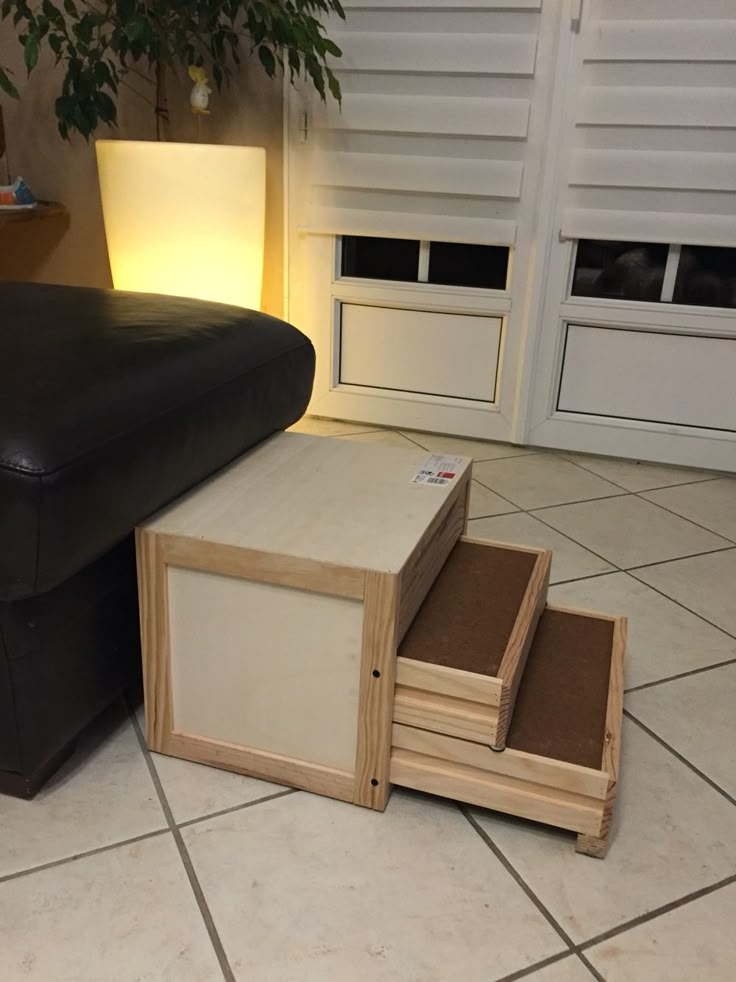 a black leather couch sitting on top of a tile floor next to a wooden box