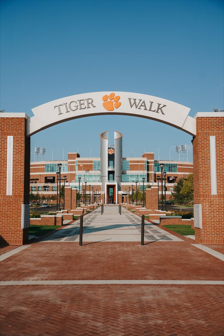 the entrance to tiger walk in front of an orange brick building with white arches over it