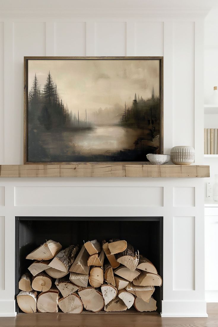 a fireplace with logs stacked in front of it and a painting on the wall above