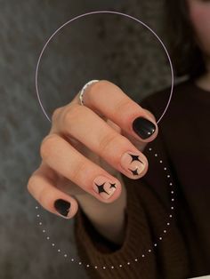 a woman with black and white nail polish holding up a circular object in her hand