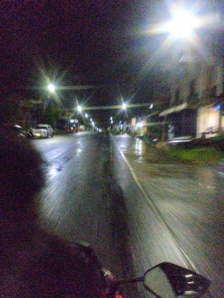 a person riding a bike on a city street at night with the headlights turned on