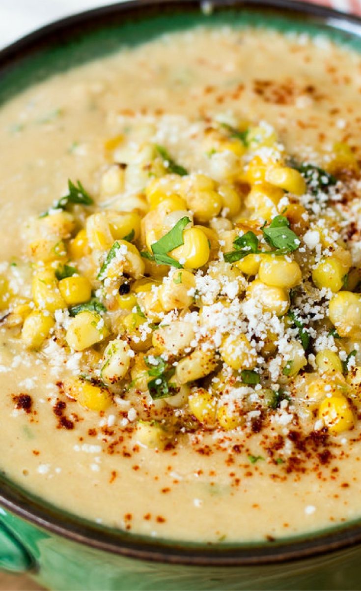 a green bowl filled with soup and garnished with parmesan cheese