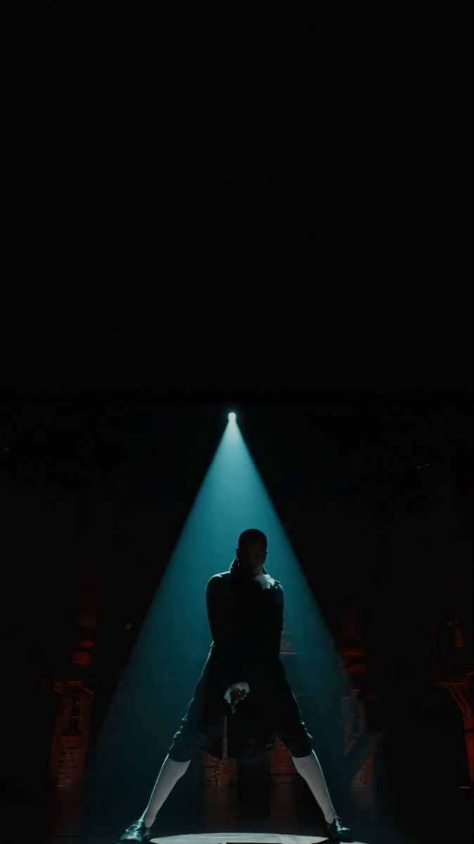 a man standing on top of a stage in front of a microphone and spotlights