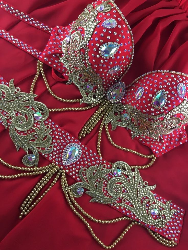 two red and gold garters are laying on a red satin sheet with beads