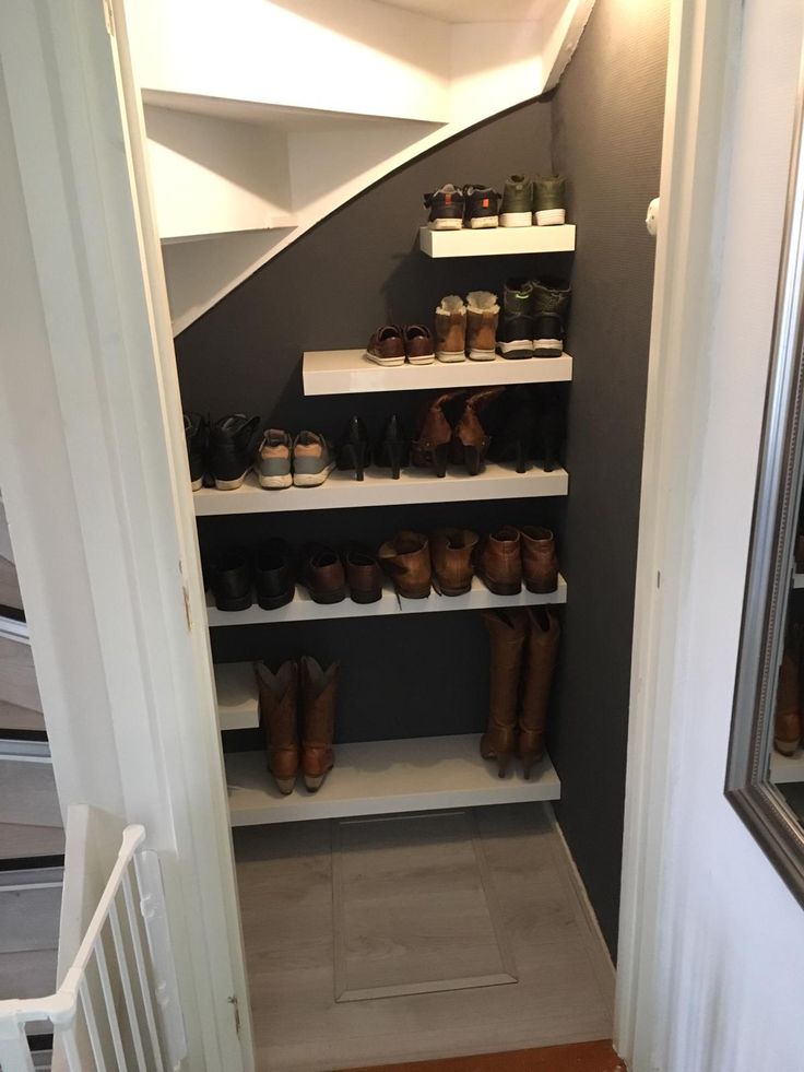 there are many pairs of shoes on the shelves in this closet that is under the stairs