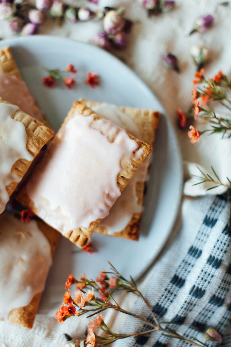 a white plate topped with pastries on top of a checkered table cloth next to flowers