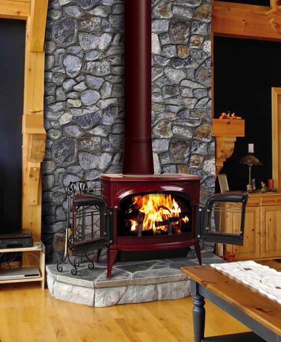 a wood burning stove sitting inside of a living room next to a table and chair