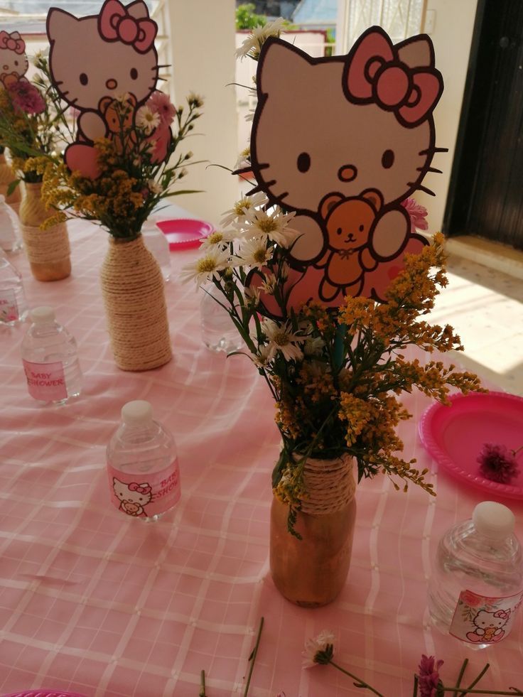 two vases with flowers and hello kitty cutouts in them sitting on a table