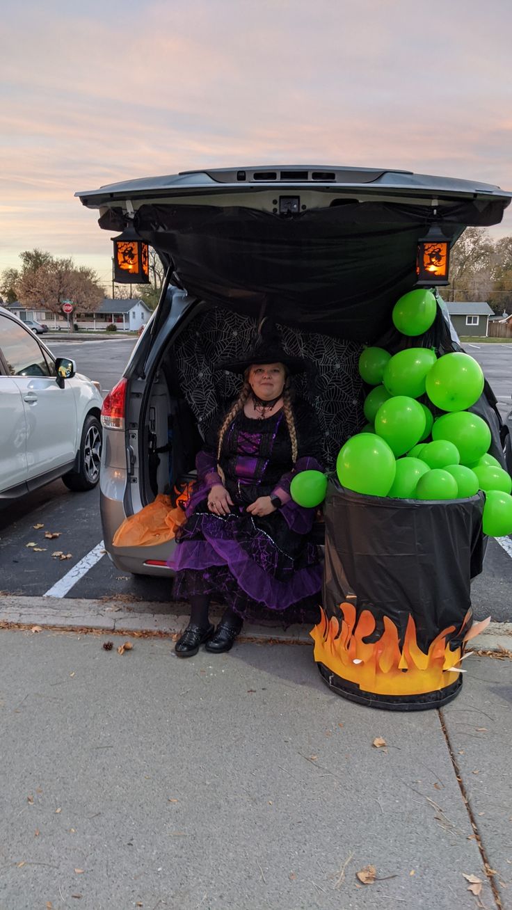 a woman sitting in the back of a car with balloons on it's trunk