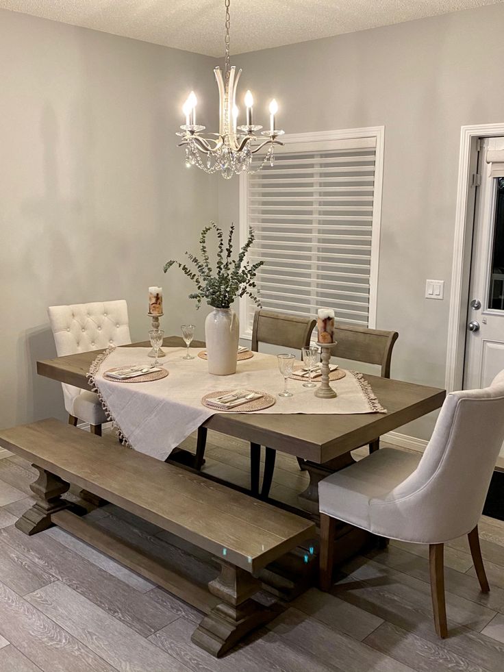 a dining room table with white chairs and a bench