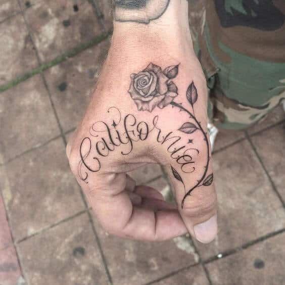 a person with a rose tattoo on their left hand and the word california written in cursive writing