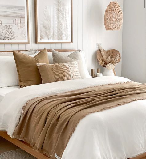 a bed with white sheets and brown pillows