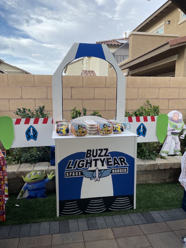 a buzz lightyear ice cream stand in front of a house with decorations around it