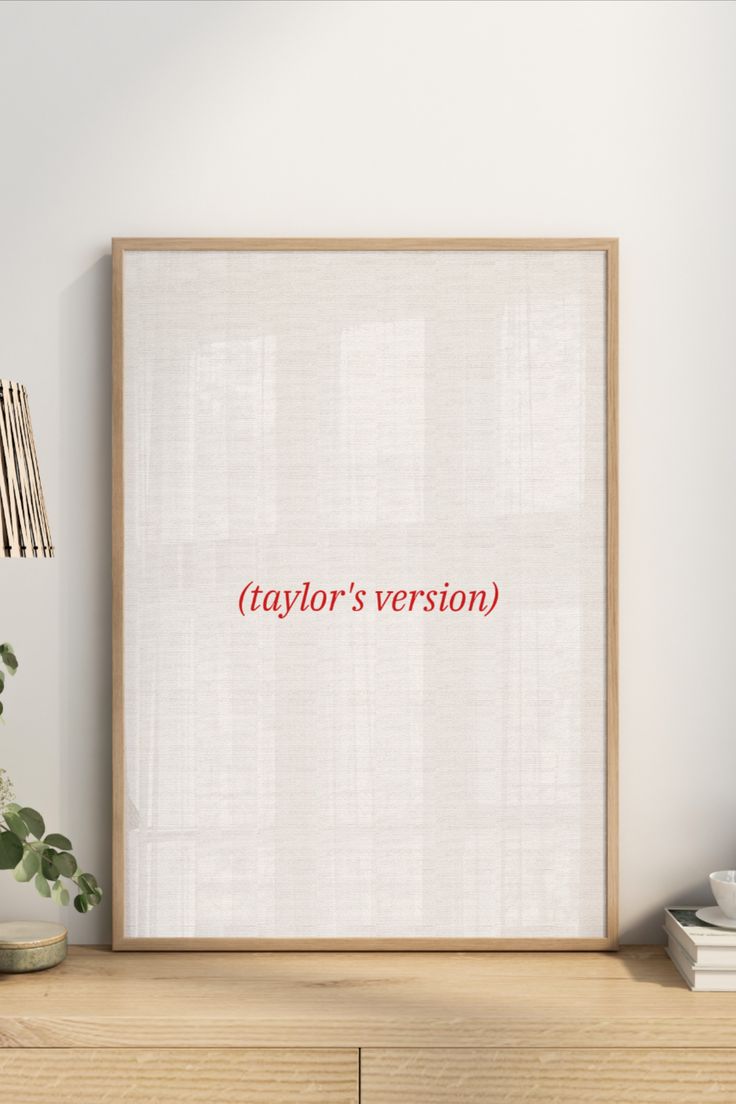 a white framed poster with the words taylor's version on it next to a potted plant