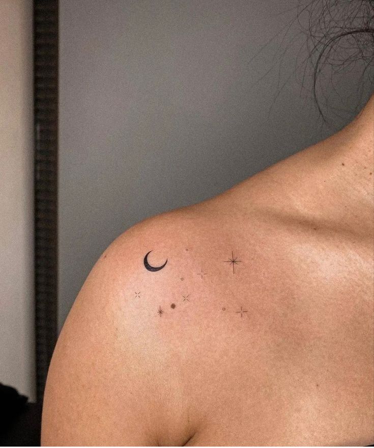 the back of a woman's shoulder with a crescent and star tattoo on it