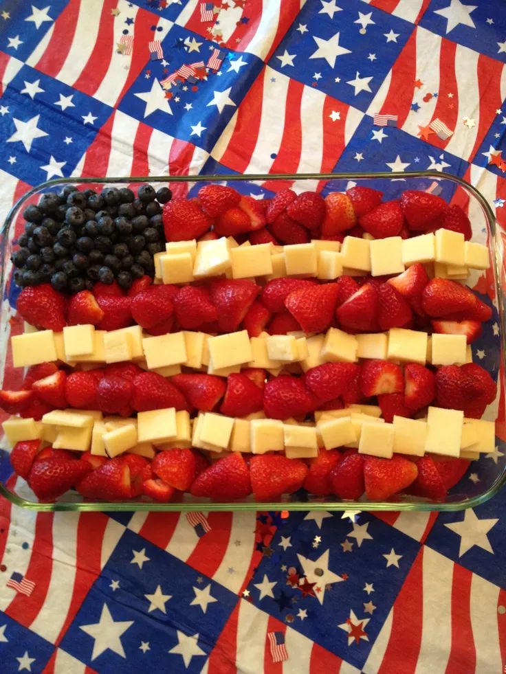 an american flag made out of strawberries, cheese and blueberries in a glass dish