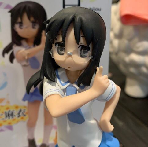 a plastic figurine of a girl with glasses holding her arm out to the side