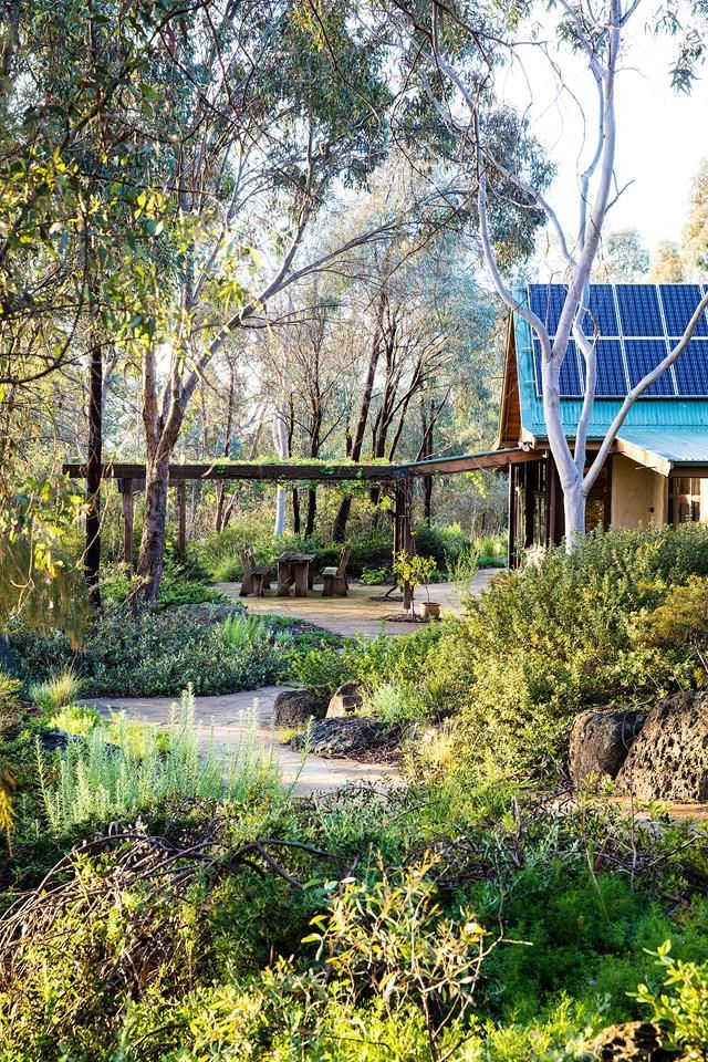 the house is surrounded by trees and bushes, with a walkway leading up to it