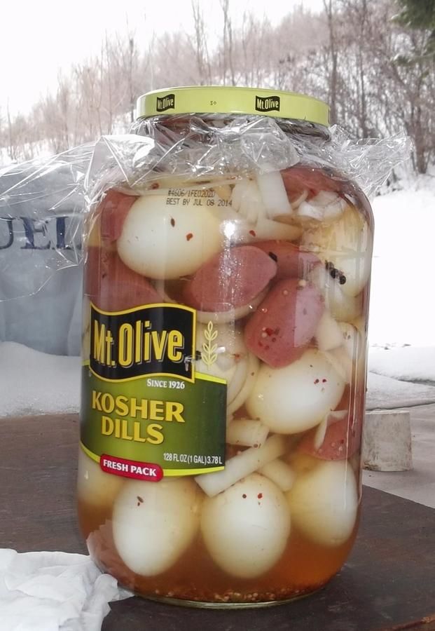 a jar filled with pickled onions sitting on top of a wooden table in the snow