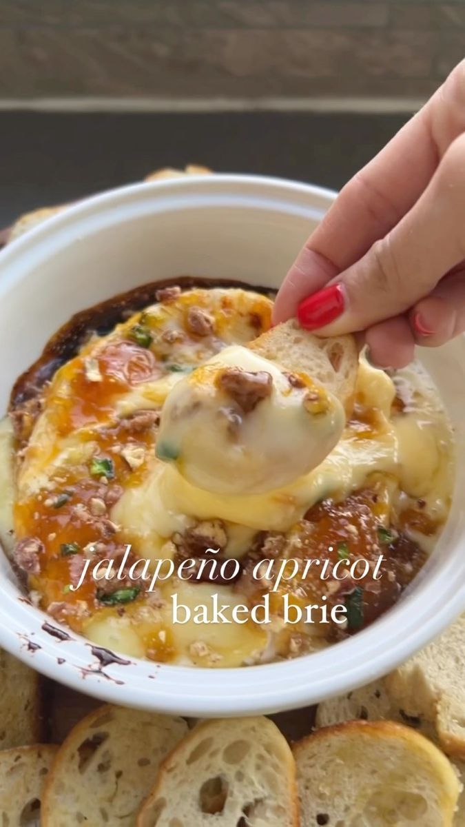 a person dipping cheese on top of bread in a white bowl with the words italian appetizer baked brie above it