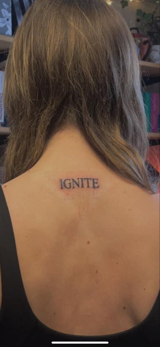 the back of a woman's neck with an inscription on it that reads ignite