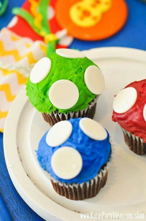 three cupcakes on a paper plate with blue and green frosting