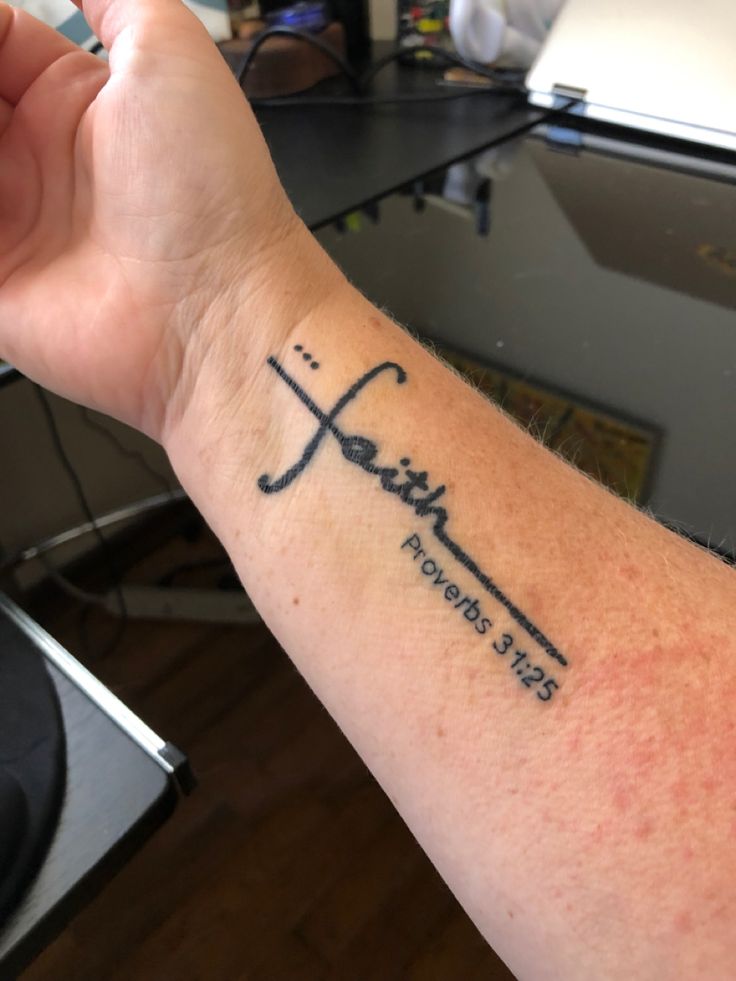 a person with a tattoo on their arm that says faith and has a cross in it