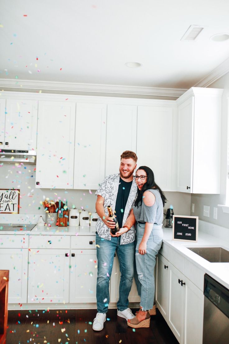 a man and woman standing in a kitchen with confetti falling from the ceiling