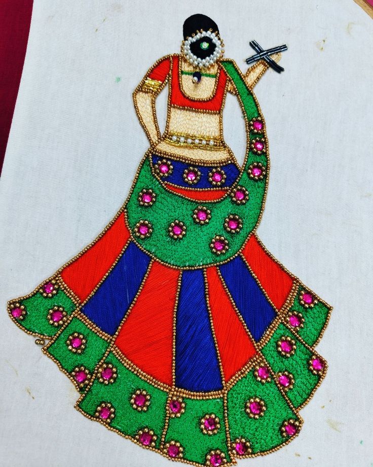 an embroidered piece of art depicting a woman in a colorful dress with a cross on her shoulder