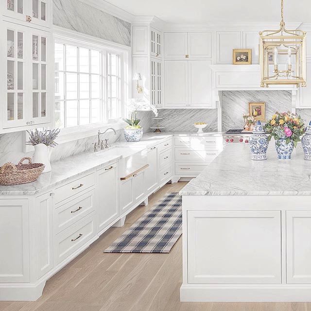 a large kitchen with white cabinets and marble counter tops