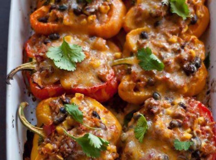 stuffed bell peppers in a casserole dish with cilantro and parsley