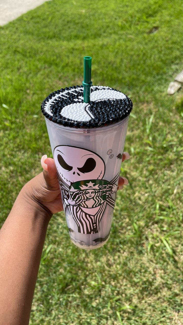 someone holding up a starbucks cup with a skeleton design on the lid and straw in their hand