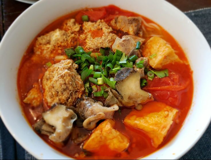 a white bowl filled with lots of food on top of a table