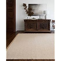 a large white rug in the middle of a room with a wooden dresser and mirror