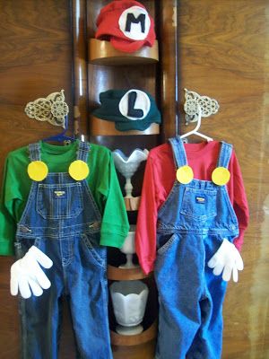 two children's overalls and hats are hanging on a shelf in front of a wall