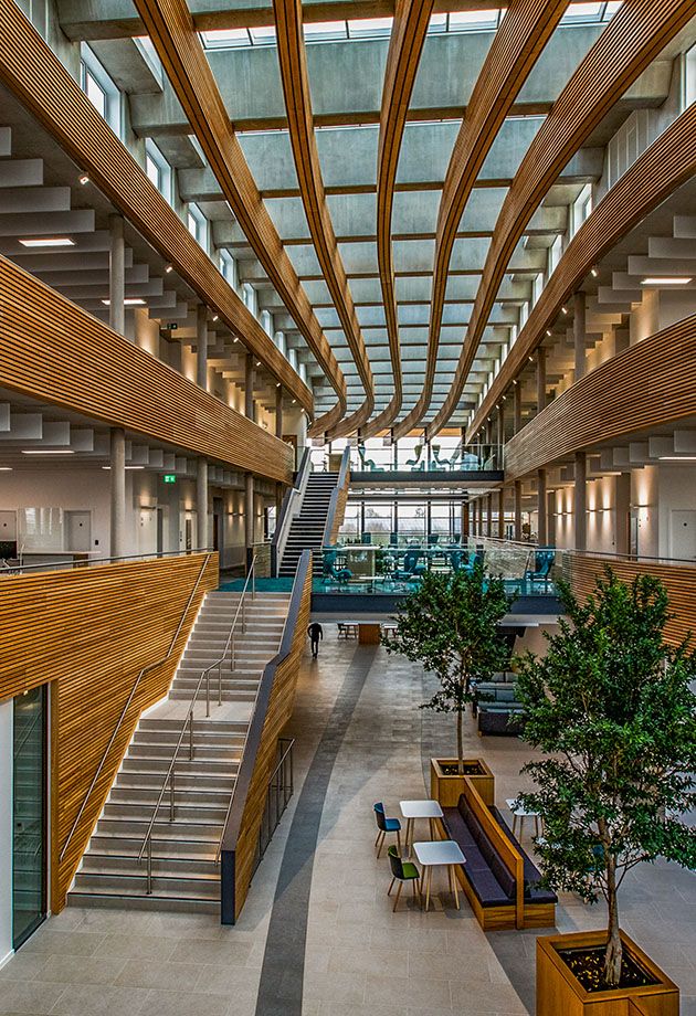 the inside of an office building with stairs and tables in front of them, as well as plants