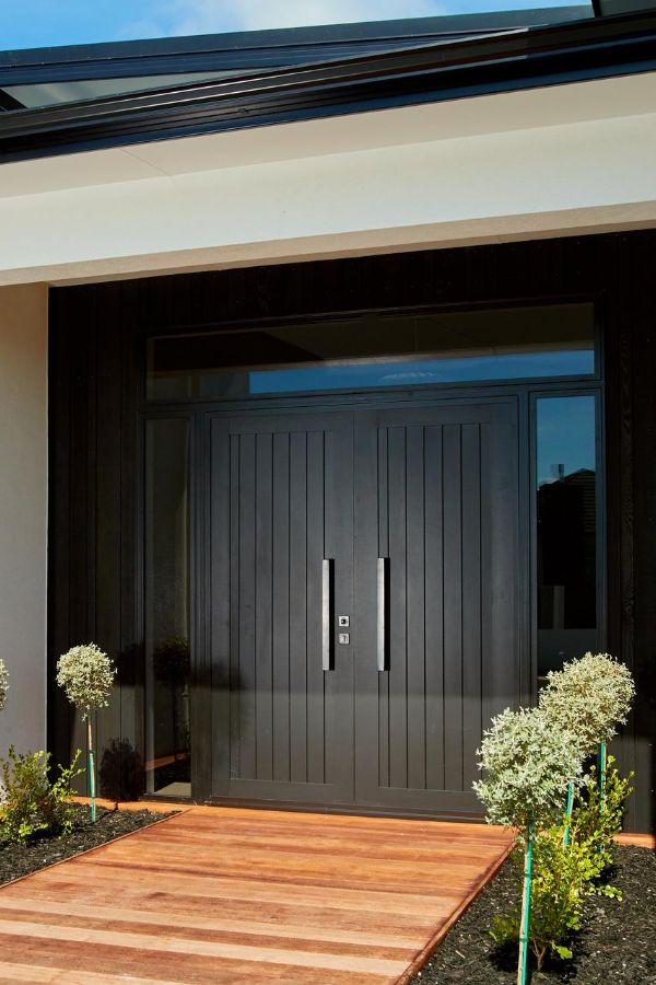 the front entrance to a modern home with wooden steps leading up to it's entry door