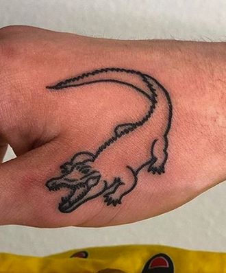 a small lizard tattoo on the left side of the hand is shown in black ink