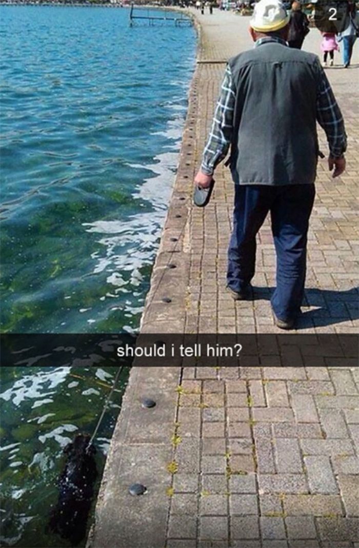 a man walking along the edge of a body of water next to a brick walkway