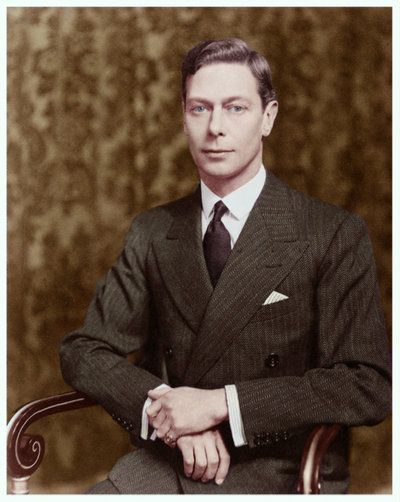 an old photo of a man in a suit and tie sitting on a chair with his arms crossed