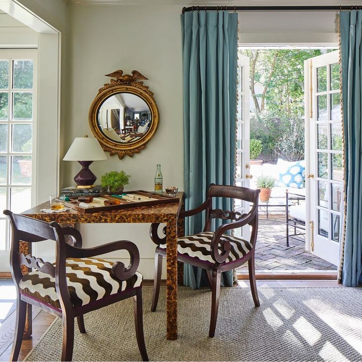 a living room with two chairs and a table in front of a mirror on the wall