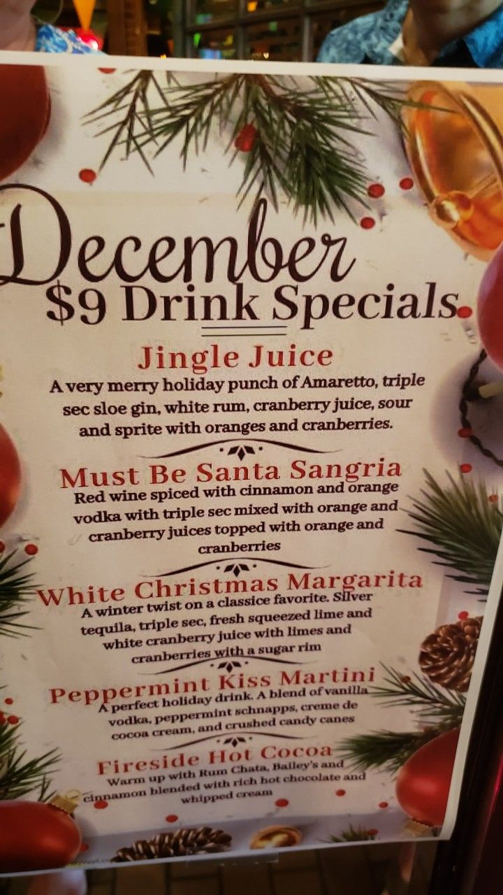 a sign with drinks on it in front of a christmas tree