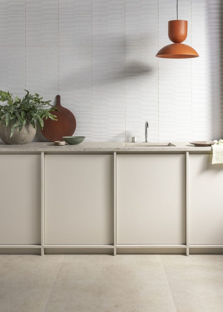 a kitchen with white cabinets and an orange lamp